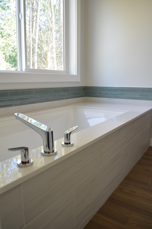 A tiled-in tub with a chrome faucet