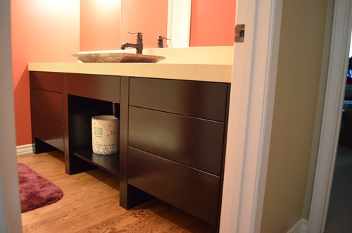 A bathroom vanity made of dark stained wood and a stone sink