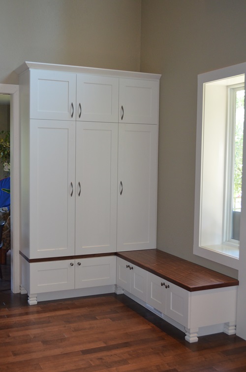 An entryway sitting area with a full height closet and a low bench with a wooden top